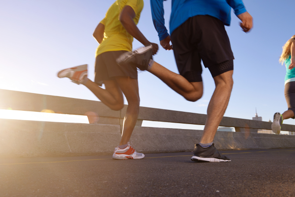 Three individuals jogging across a bridge