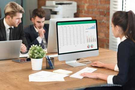 Business executives gathered around a table with a computer screen for a collaborative discussion