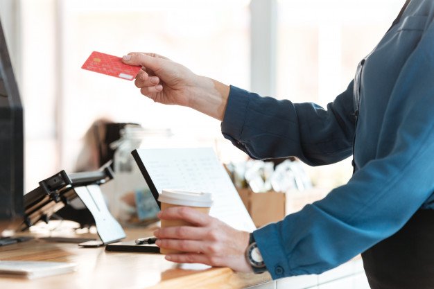 A person holding a credit card at a counter