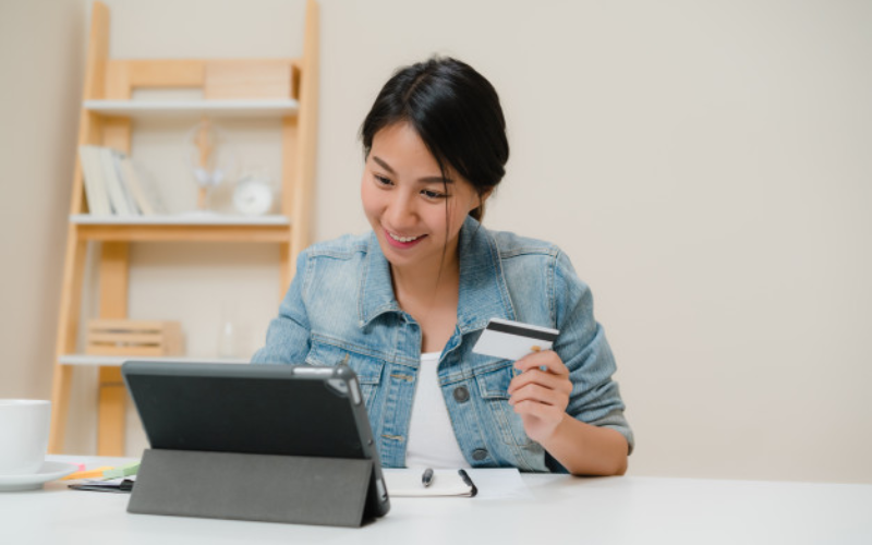 Woman uses tablet, holds credit card for online transactions
