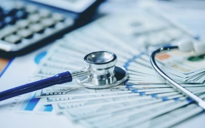 A medical stethoscope and money placed on a desk.